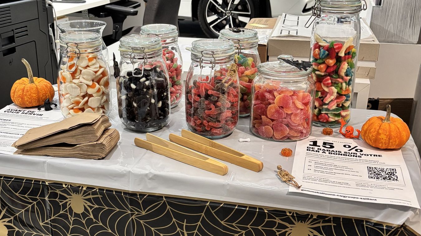 Bar à bonbons Gomme Balloune monté dans une concession automobile: pots de jujubes, pinces en bambou et sacs en papier.